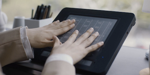 A pair of hands on top of the Dot Pad A pair of hands on top of the Dot Pad