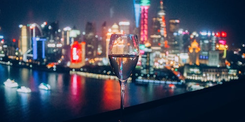 A flute of sparkling drink in front of the skyline of Shanghai, China A flute of sparkling drink in front of the skyline of Shanghai, China