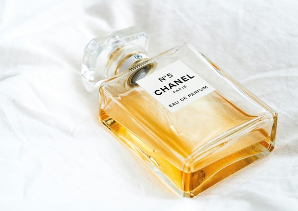 A Chanel No. 5 bottle on a white bedsheet A Chanel No. 5 bottle on a white bedsheet