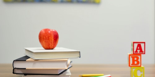 An apple on top of a pile of books next to some alphabet wood blocks An apple on top of a pile of books next to some alphabet wood blocks