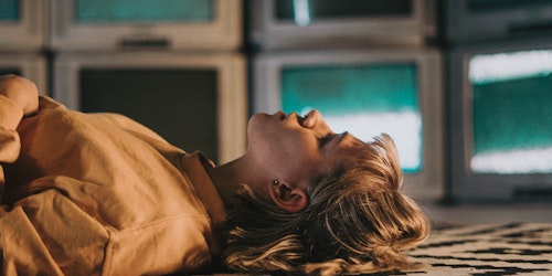 Girl lying on floor surrounded by TVs Girl lying on floor surrounded by TVs
