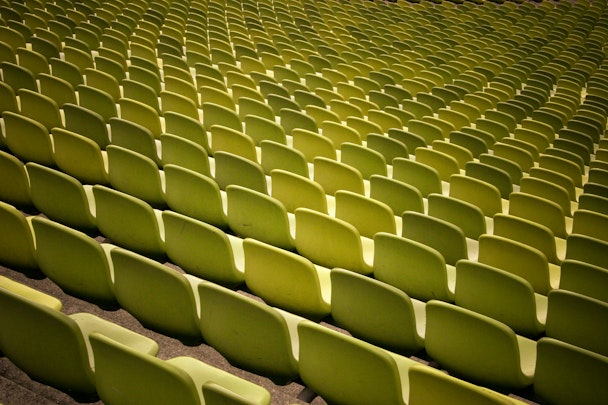 The backs of green empty rows of chairs at a stadium The backs of green empty rows of chairs at a stadium