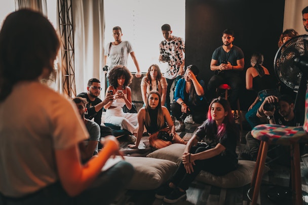 People sat on the floor listening to a woman talking at the front People sat on the floor listening to a woman talking at the front