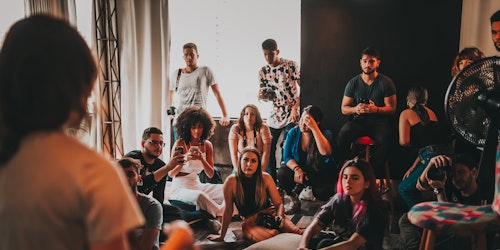 People sat on the floor listening to a woman talking at the front People sat on the floor listening to a woman talking at the front