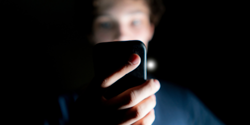 Guy holding cell phone in dark room Guy holding cell phone in dark room