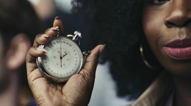 ‘Time’ is portrayed as a spectator holding a ticking stopwatch up to sprinter Emmanuel Oyinbo-Coker ‘Time’ is portrayed as a spectator holding a ticking stopwatch up to sprinter Emmanuel Oyinbo-Coker