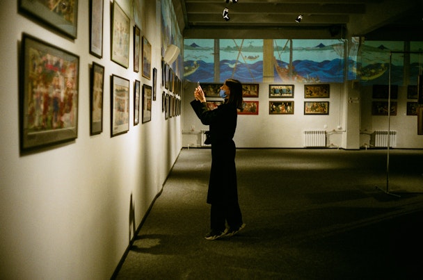 Woman wearing face mask taking a photo at an art exhibiton Woman wearing face mask taking a photo at an art exhibiton