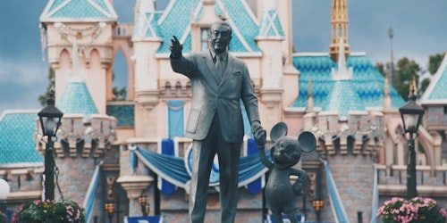 A statue of Walt Disney and Mickey Mouse, in front of a Disney pleasure resort A statue of Walt Disney and Mickey Mouse, in front of a Disney pleasure resort