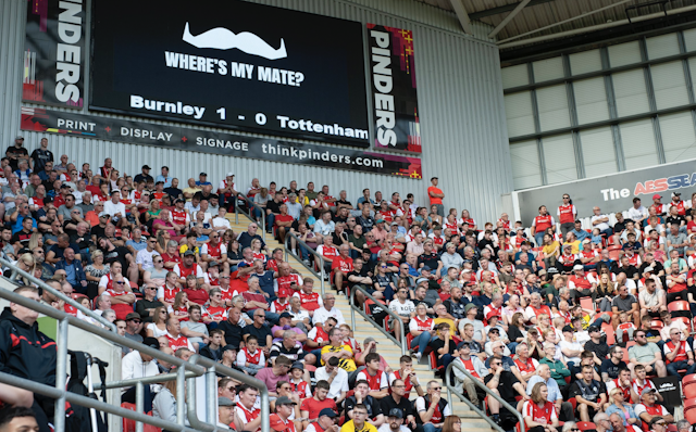 Football fans in stadium with 'Where's my mate?' ad in background Football fans in stadium with 'Where's my mate?' ad in background