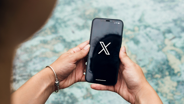 Person opening X app on their mobile phone Person opening X app on their mobile phone